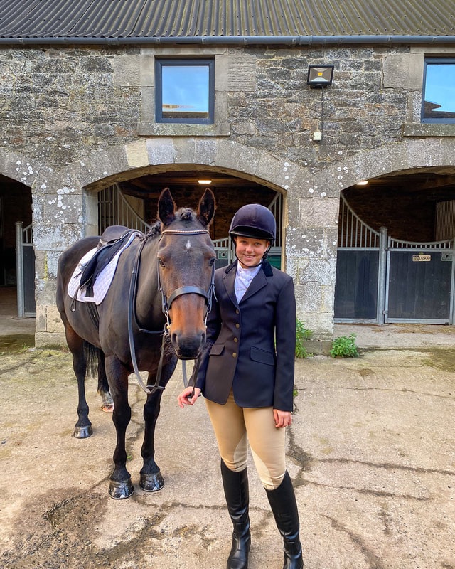 Young lady stood with her horse, Welsh D x TB gelding before their first ever dressage compeition. They are deessed smartly in the correct turnout.